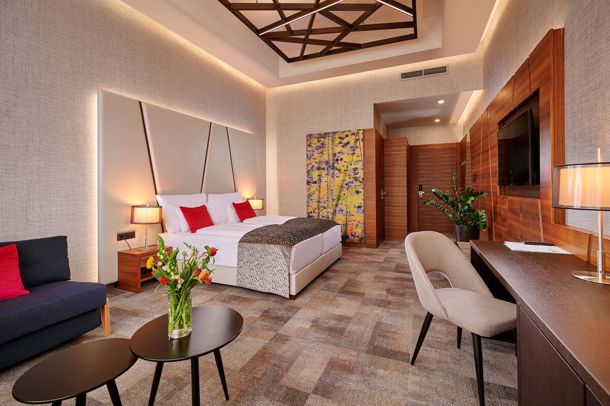 Una habitación de hotel moderna con cama, sofá, escritorio y televisor.