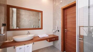 A modern bathroom with a large mirror, a wooden vanity, a sink, and a glass shower enclosure.
