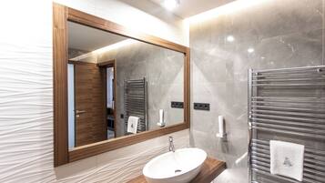 A modern bathroom with a wooden vanity, a large mirror, a white sink, and a glass shower enclosure.