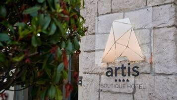 A sign for 'artis Boutique Hotel' with a geometric design on the wall.