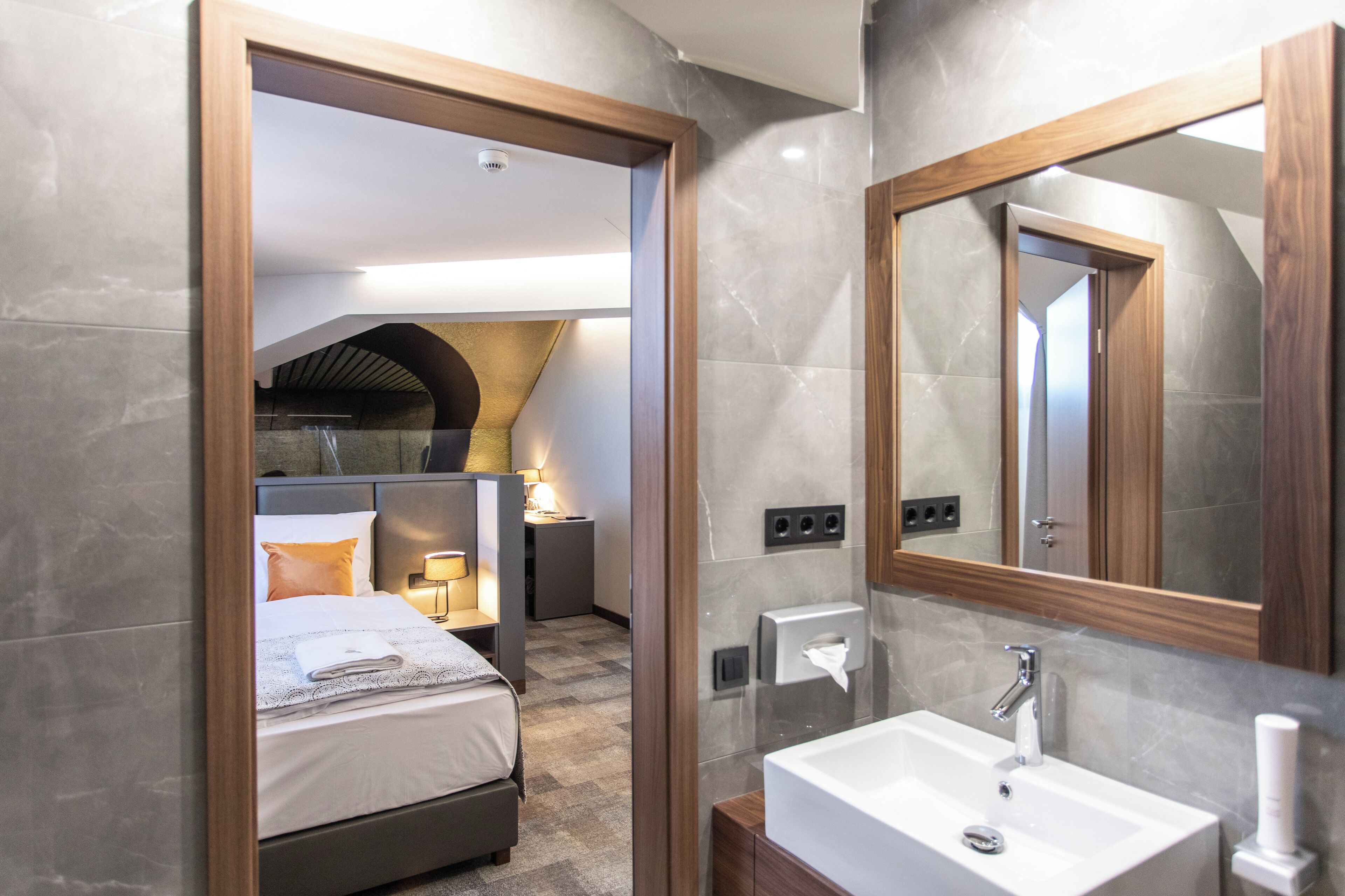 Ein modernes Hotelzimmer mit einem großen Bett, einem Badezimmer mit einem großen Spiegel und einer kleinen Küchenzeile.
