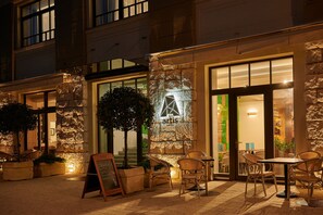 Un área de café al aire libre con paredes de piedra, muebles de madera y un letrero que dice 'artis'.