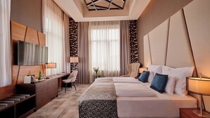 Una habitación de hotel moderna con una cama grande, un escritorio, un televisor y una mesita con una lámpara.