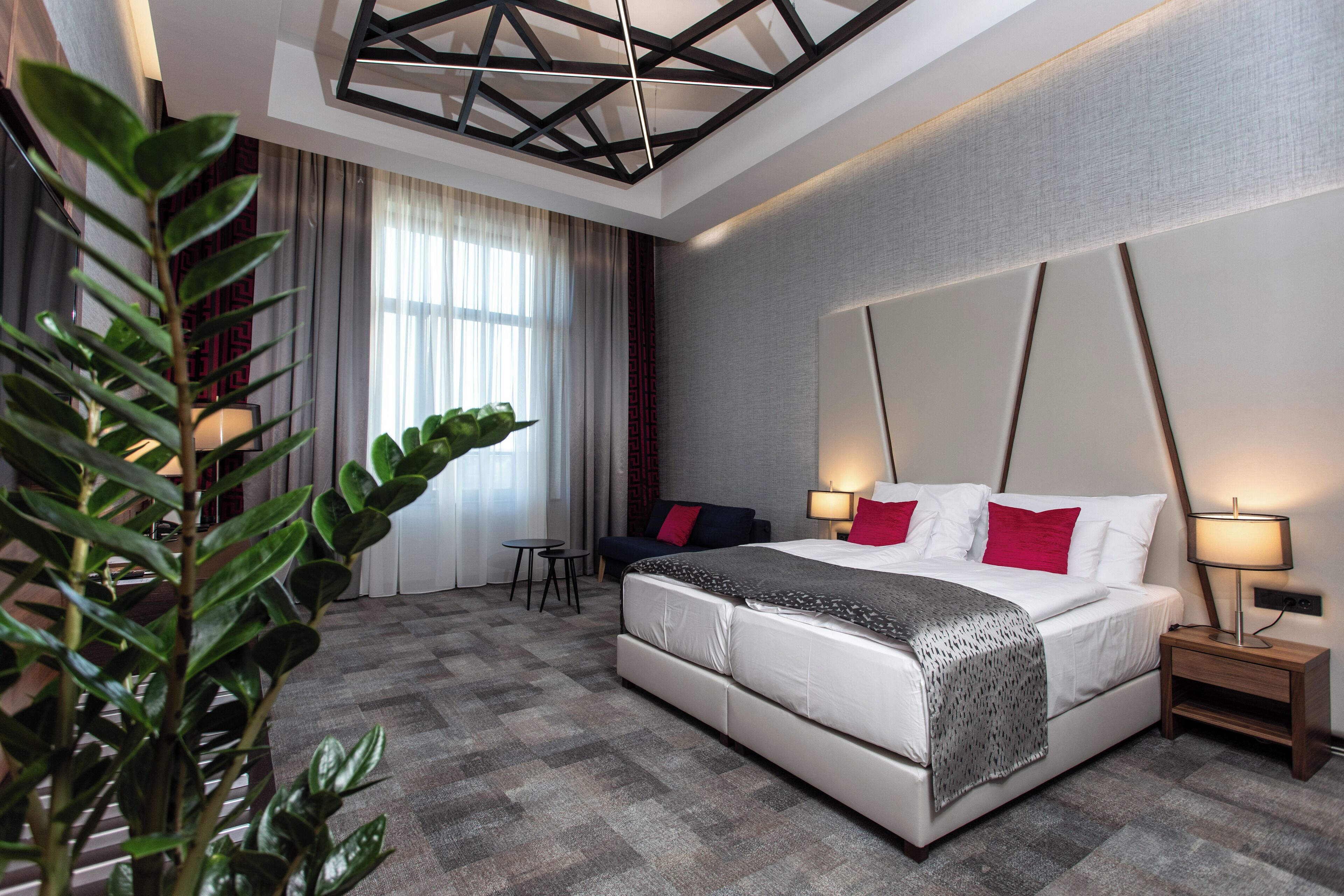 A modern hotel room with a large bed, a desk, and a chair.