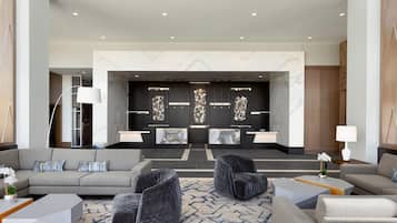 A modern lobby with a reception desk, seating area, and a decorative wall.