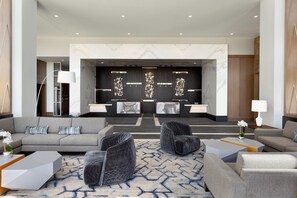 A modern lobby with a reception desk, seating area, and a decorative wall. - Hilton Alpharetta Atlanta (Alpharetta)