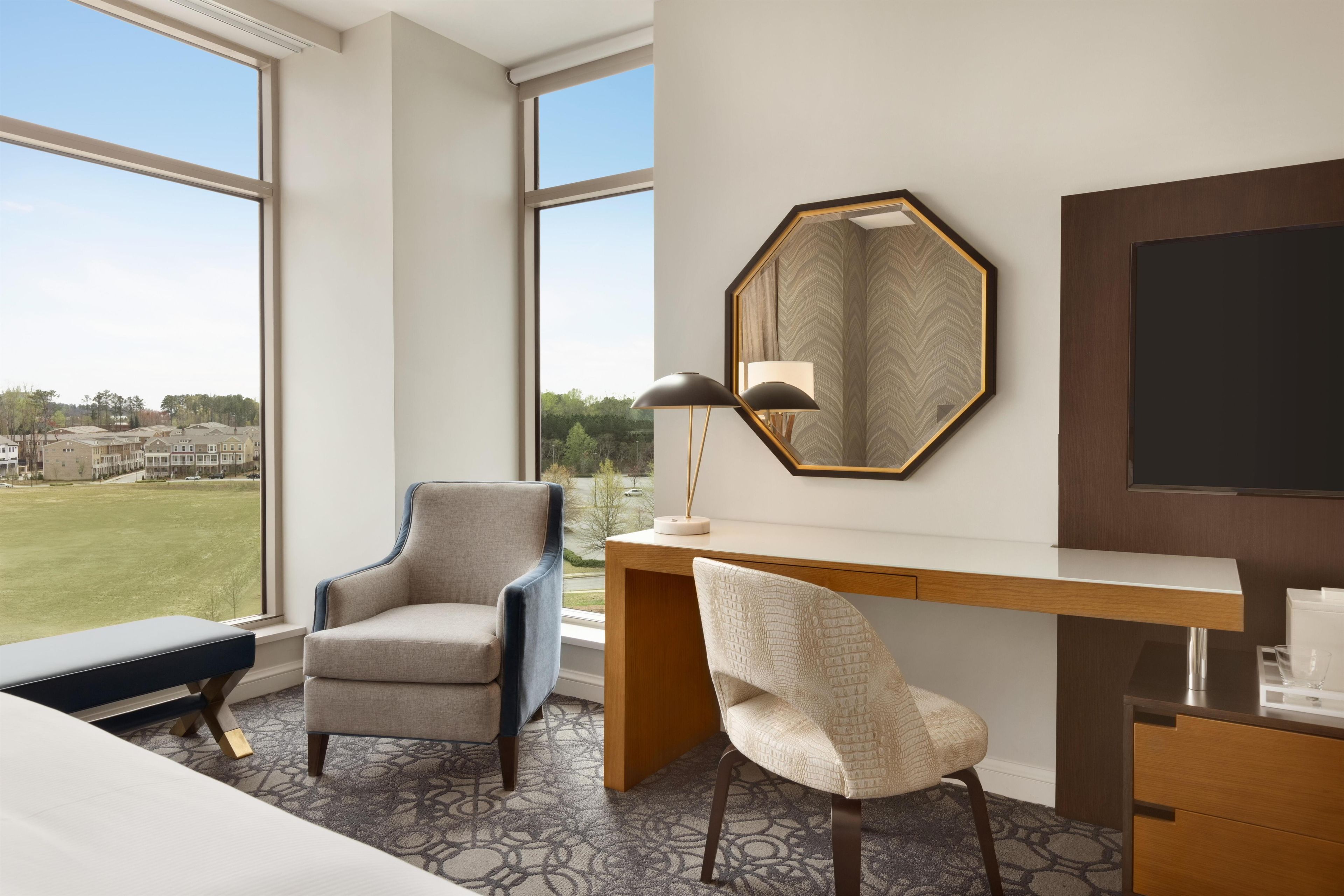 Una habitación de hotel con un ventanal grande, un escritorio, una silla y una cama.