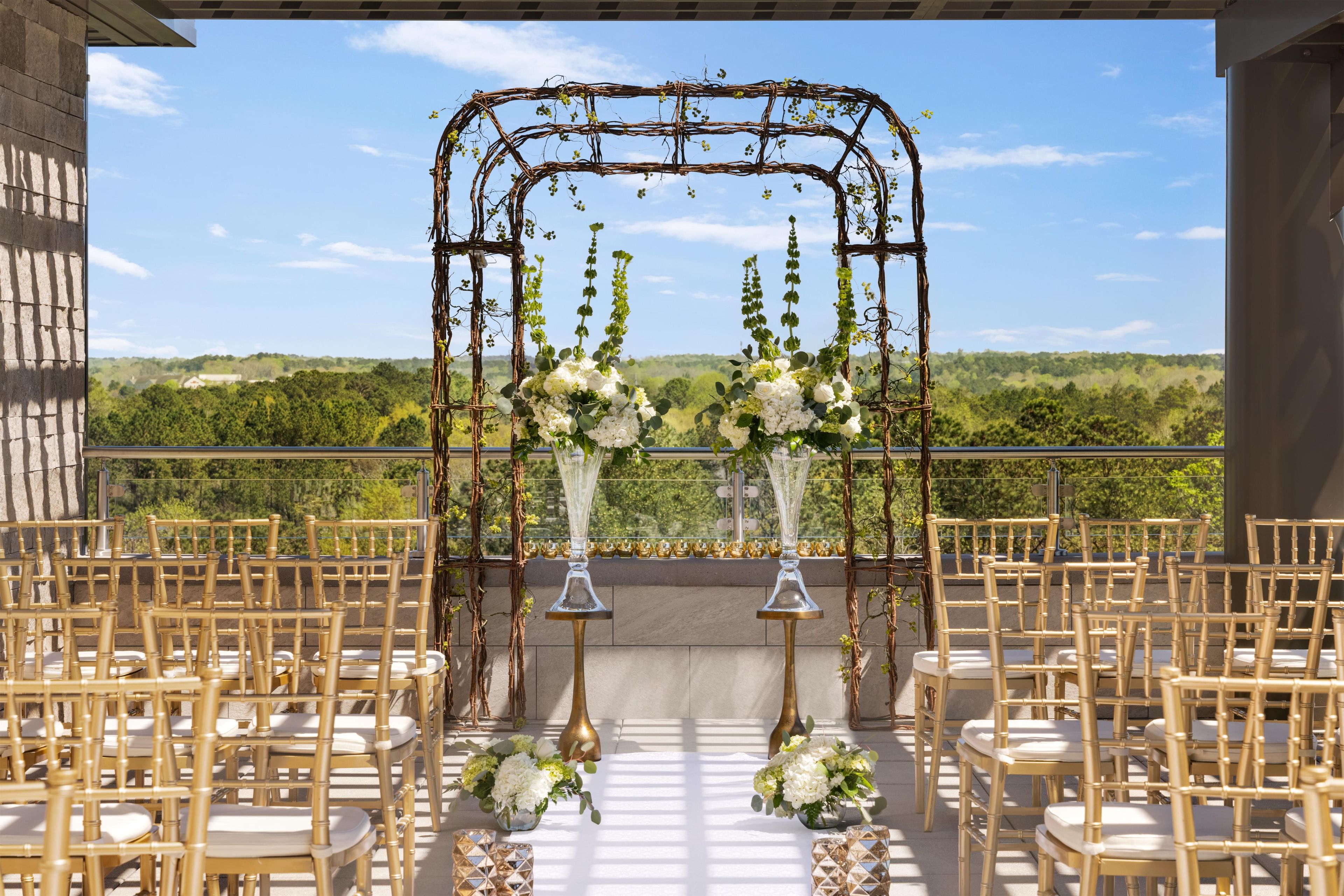 Cerimônia de casamento ao ar livre com arco de videira e arranjos florais.