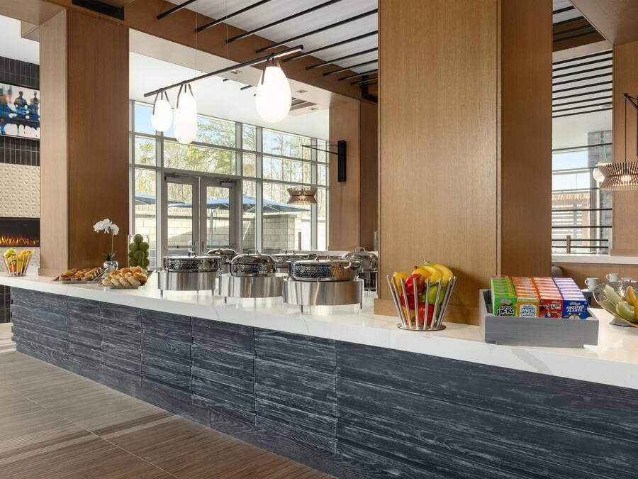 A modern kitchen with a central island, stainless steel appliances, and a variety of breakfast items.