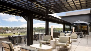 An outdoor patio with seating, a table, and a view of the landscape. - Hilton Alpharetta Atlanta (Alpharetta)