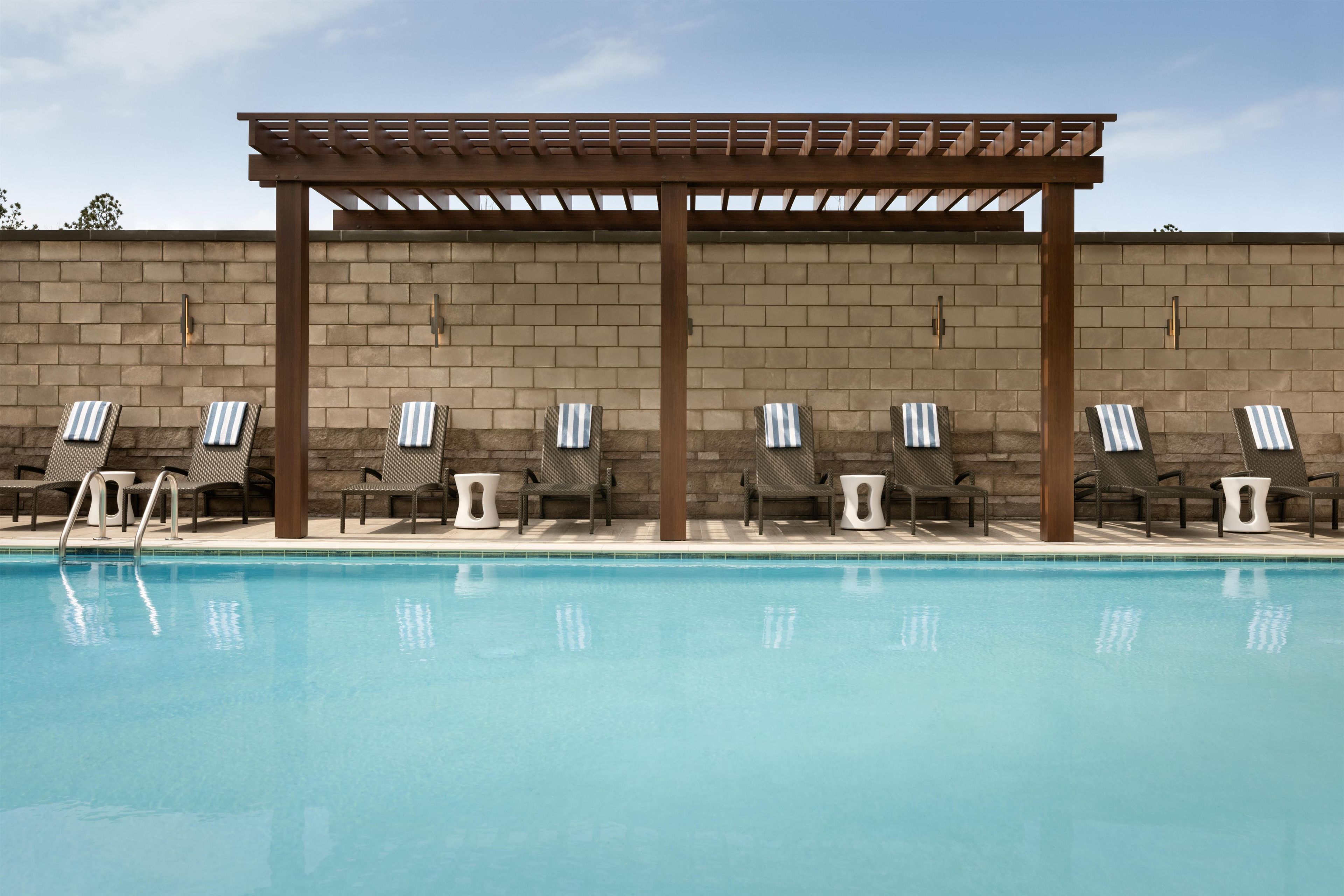 A poolside area with lounge chairs and a pergola structure.