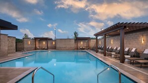 A rectangular pool with clear blue water, surrounded by lounge chairs and a pergola with lights. - Hilton Alpharetta Atlanta (Alpharetta)