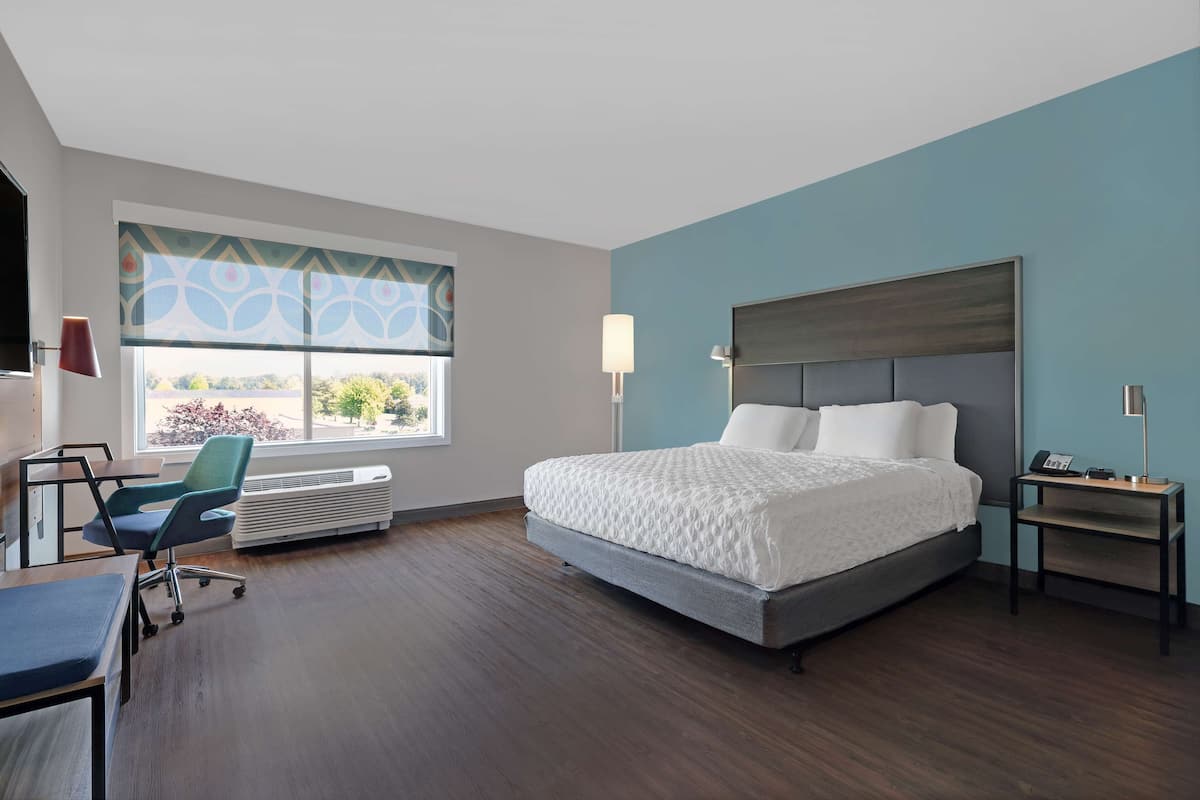 Ein modernes Hotelzimmer mit einem großen Bett, einem Schreibtisch, einem Stuhl und einem Fenster mit Blick.