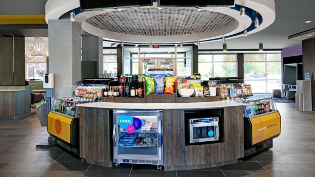 Een modern, rond bedieningspunt met een gekoeld etalage en drankdispenser, omringd door diverse snacks en dranken.