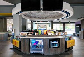 A modern, circular counter with a refrigerated display and a beverage dispenser, surrounded by a variety of snacks and beverages.