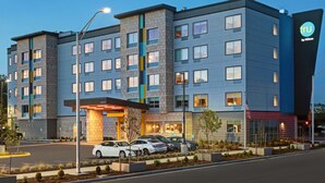 Een modern hotel met meerdere verdiepingen, een parkeerplaats en een goed verlichte entree.