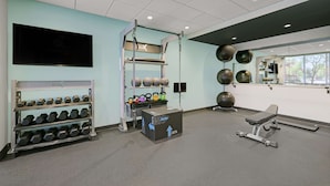 Een sportschool met gewichthefapparatuur, dumbbells, kettlebells en trainingsballen.