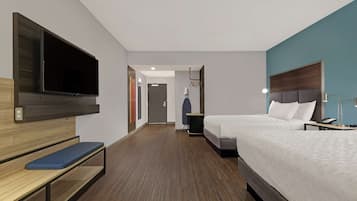 A hotel room with a bed, a bench, a TV mounted on the wall, and a door leading to another room.
