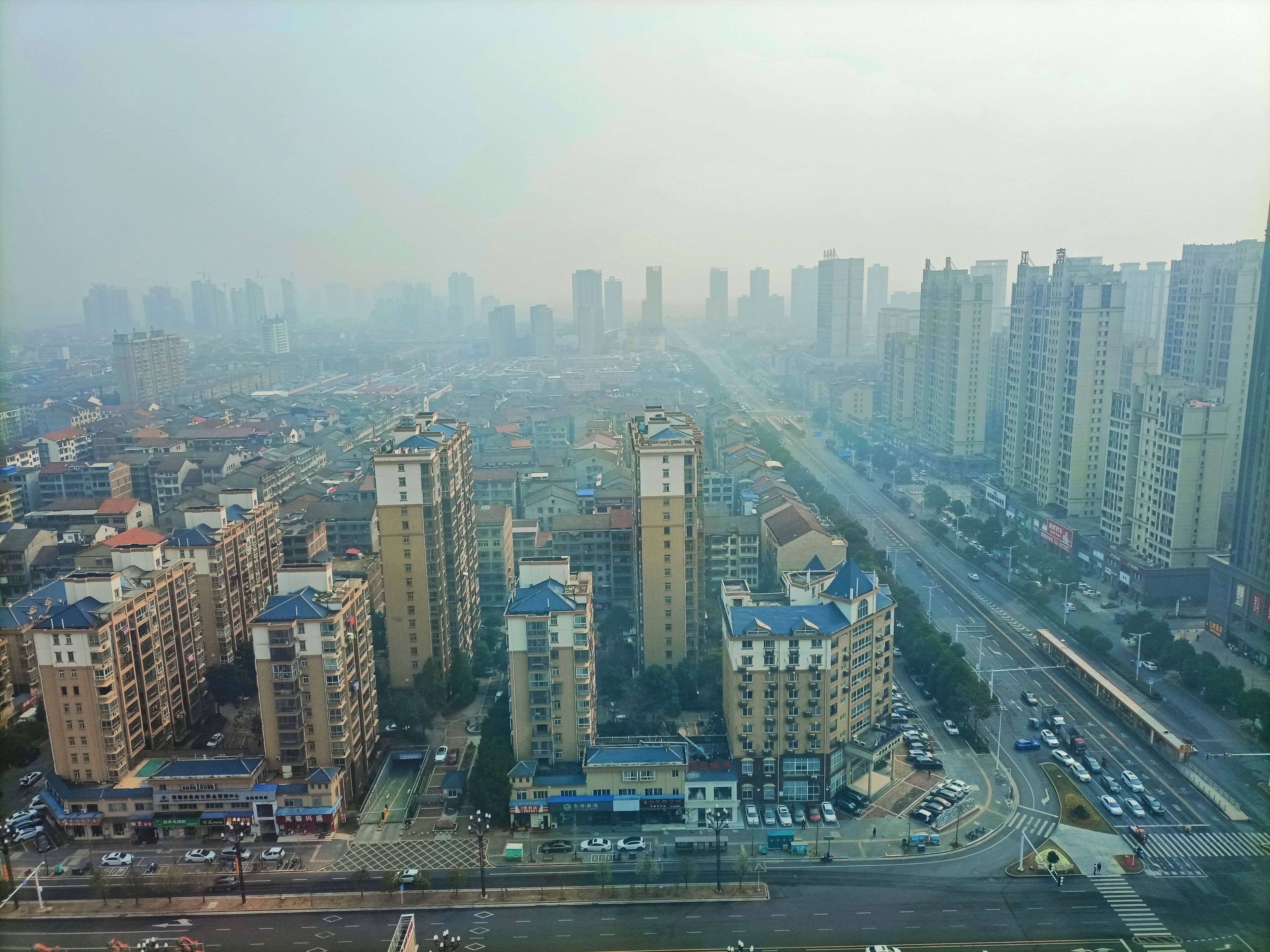 A high-rise residential area with multiple apartment buildings, a main road, and a pedestrian crossing.