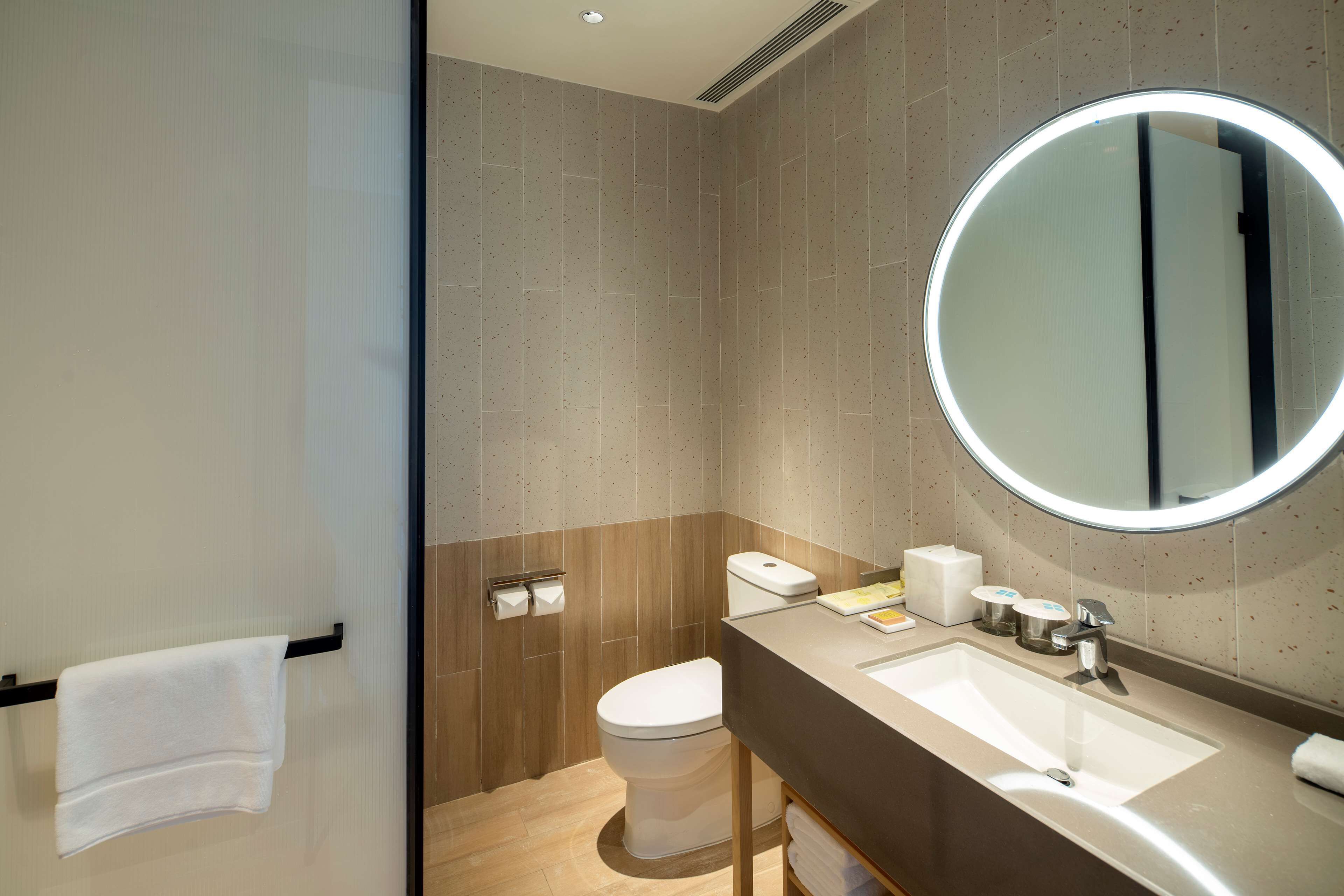 Un baño moderno con inodoro, lavamanos y espejo.