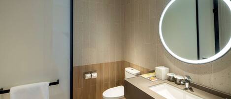 Un baño moderno con inodoro, lavamanos y espejo.