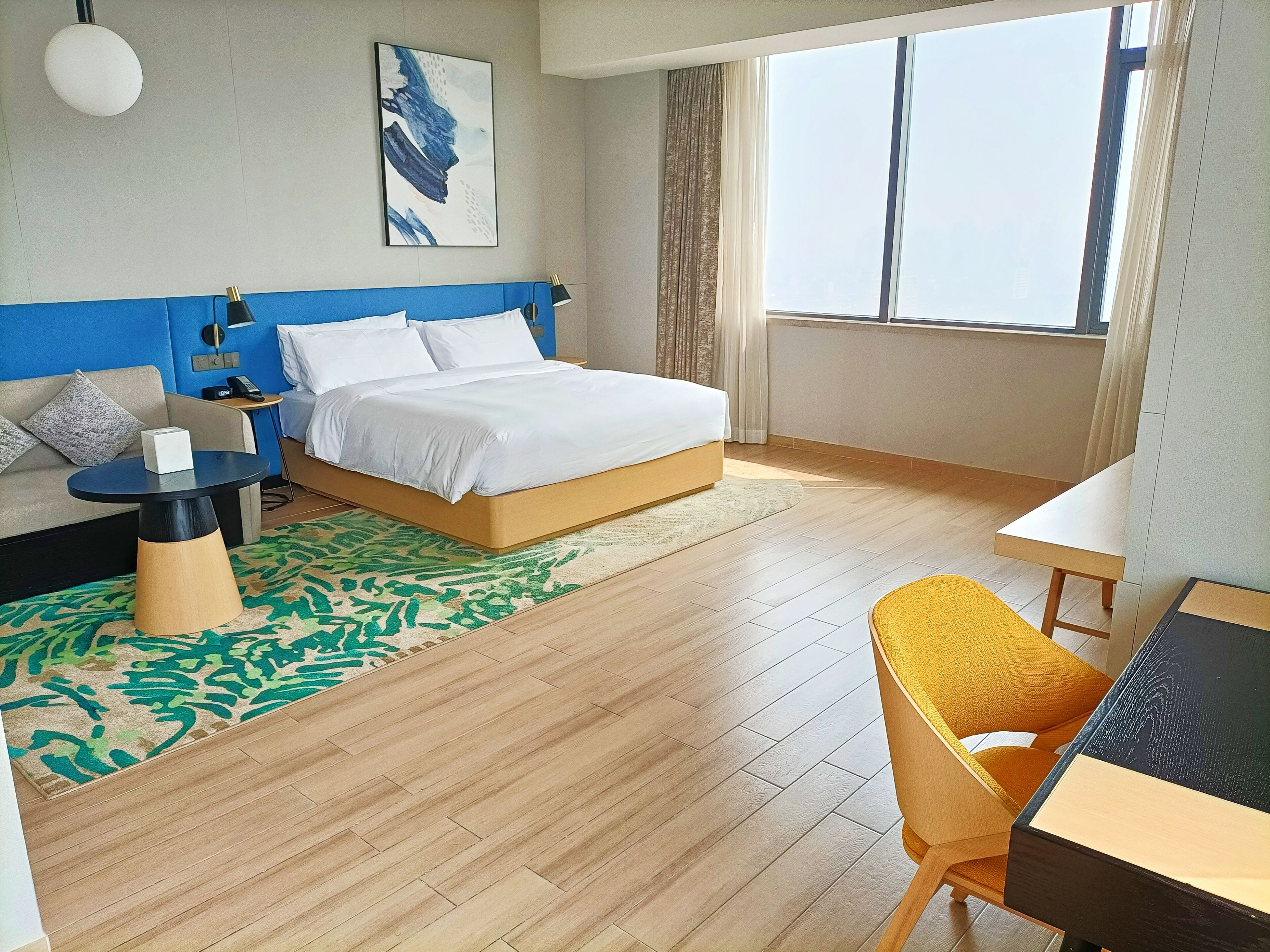 A hotel room with a bed, a sofa, a desk, and a chair.