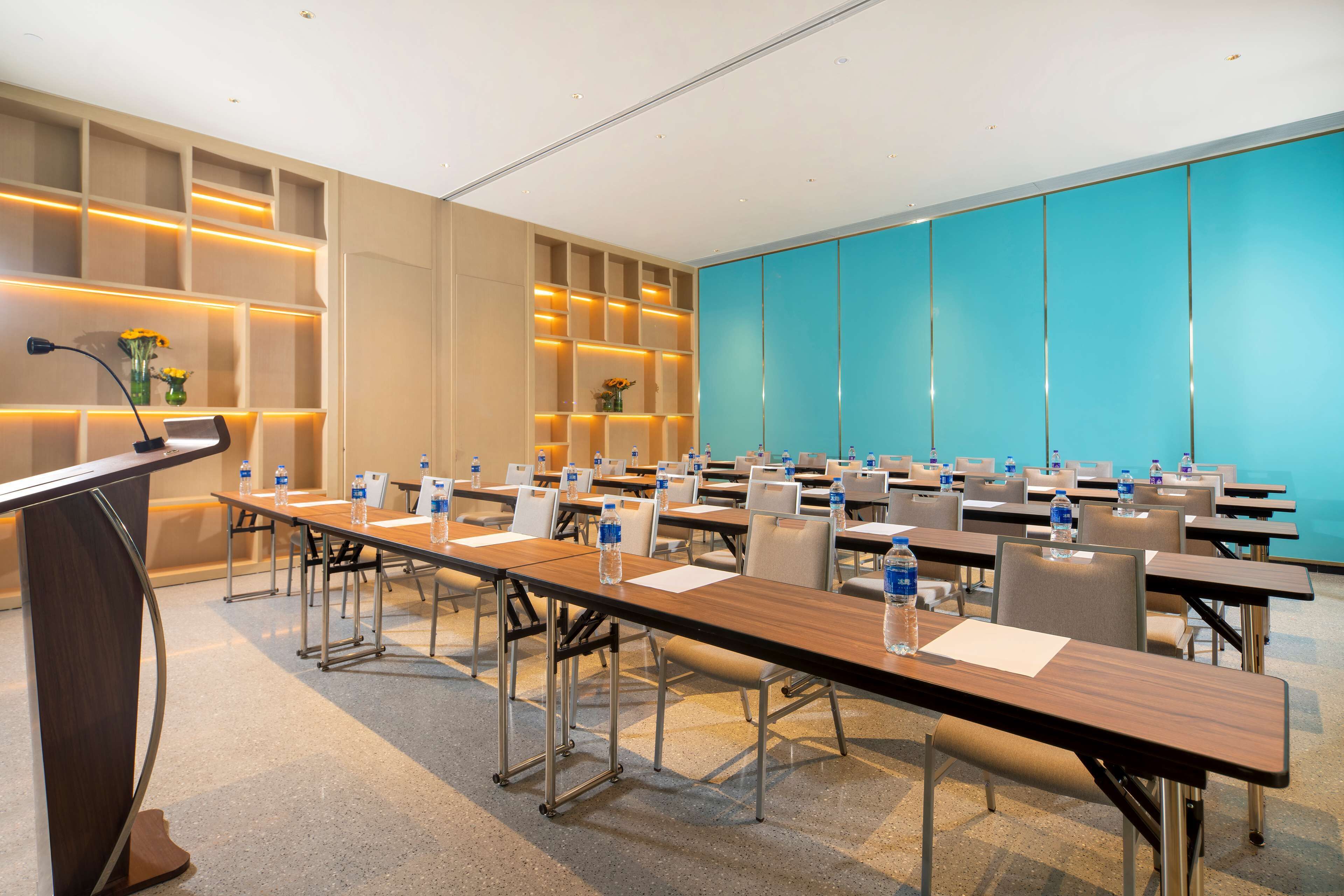 A conference room with a long table, chairs, a podium, and water bottles.