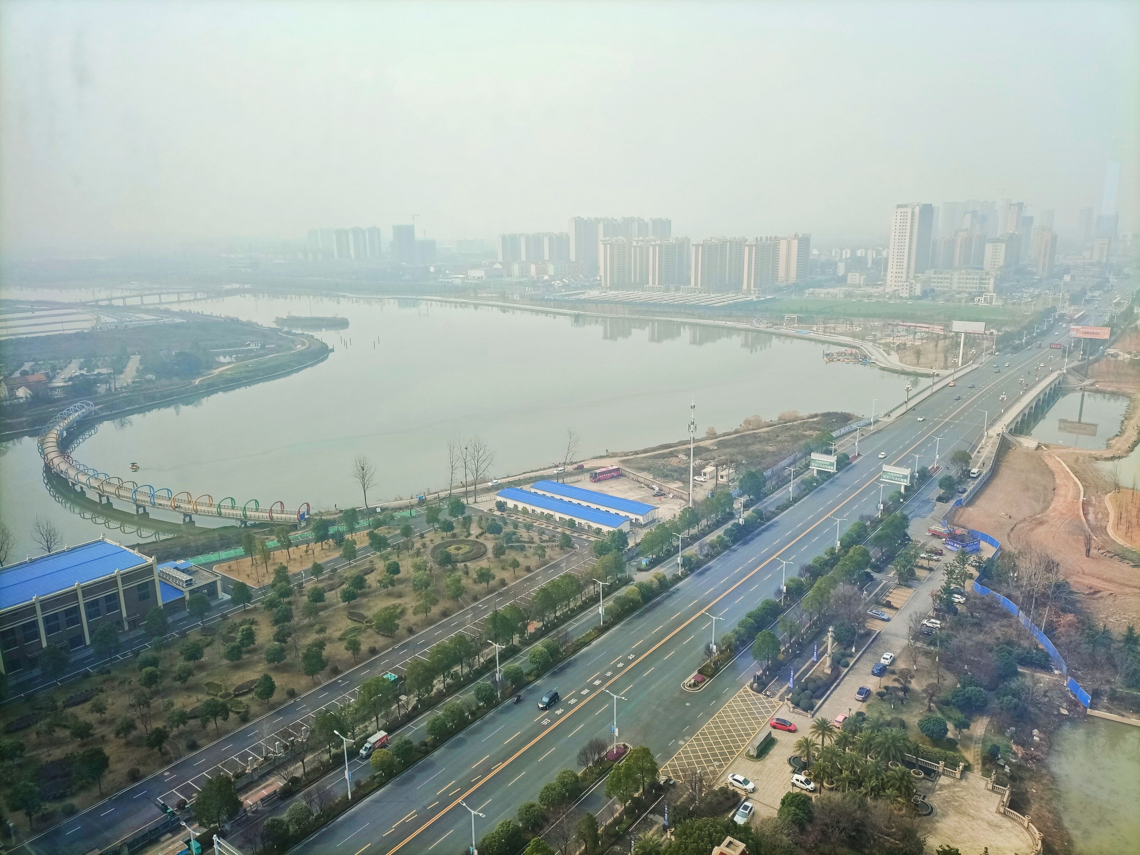 An aerial view of a cityscape with a river, a bridge, and a highway.