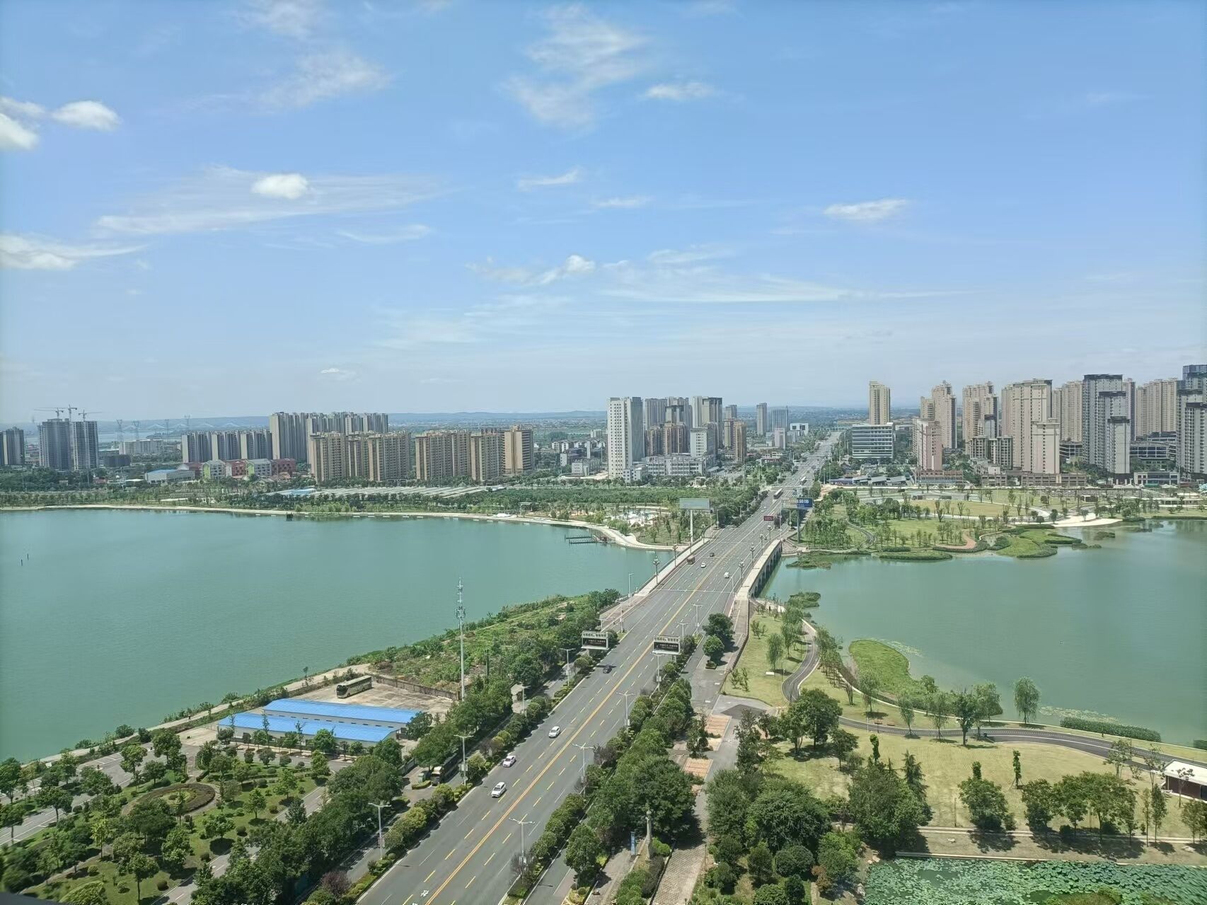 A cityscape with a prominent bridge connecting two sides, surrounded by water and greenery.