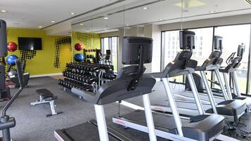 A gym with treadmills, dumbbells, and exercise balls.