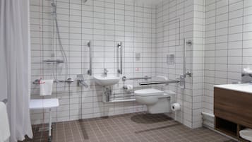 Un baño moderno con ducha, lavamanos, inodoro y tocador de madera.