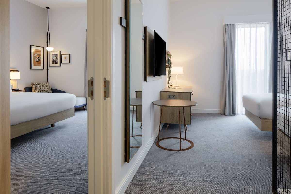 Een hotelkamer met een bed, een bureau, een stoel, een televisie en een raam met gordijnen.
