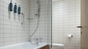 A modern bathroom with a glass-enclosed shower, a white bathtub, and three bottles of Craybreeze body wash on the wall.