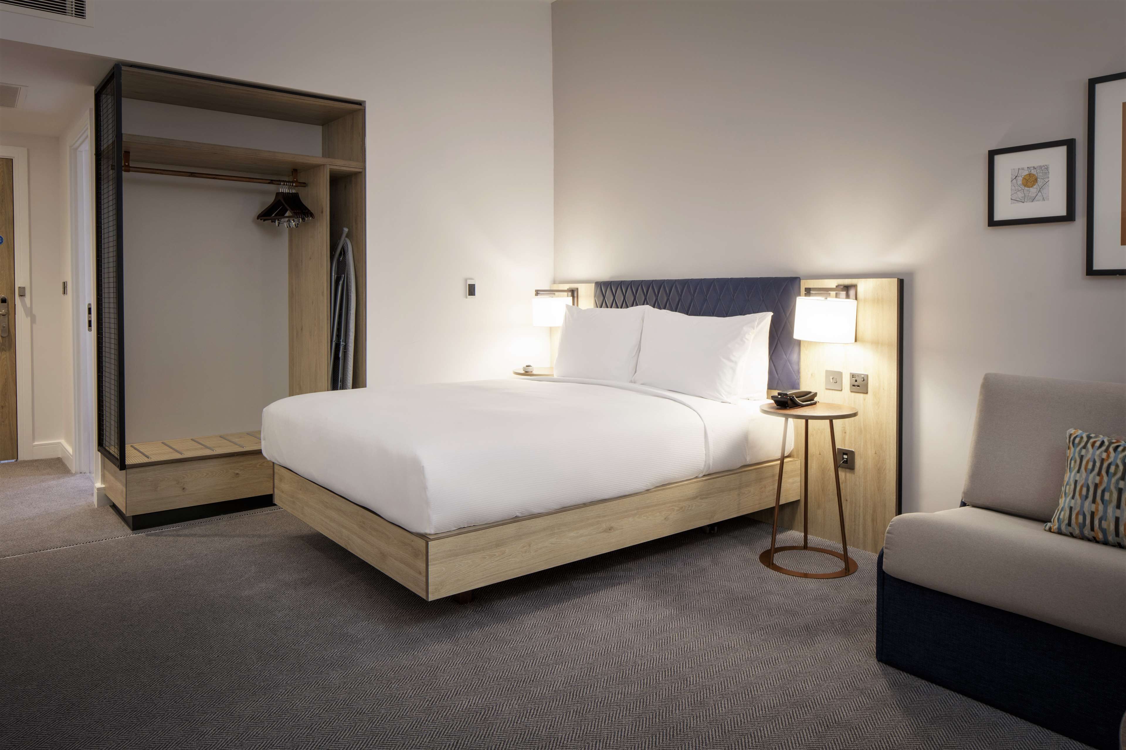Une chambre d’hôtel avec un lit, une chaise, une petite table et un dressing.