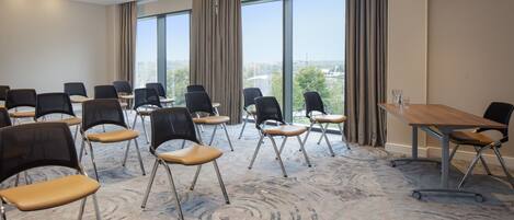 A conference room with a large table, multiple chairs, and large windows offering a view of the city.