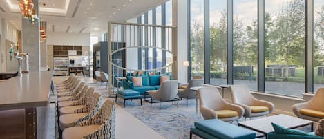 Un salón amplio con una barra larga, asientos cómodos y grandes ventanales con vistas al exterior.