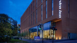Ett Hilton Garden Inn-hotell med en fasad av tegel, stora fönster och en skylt som visar varumärket.