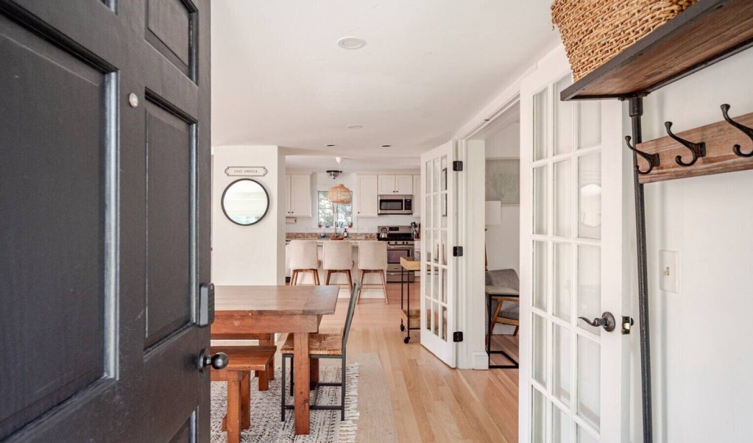 Una cocina moderna con armarios blancos, un microondas y un comedor con una mesa y sillas de madera.