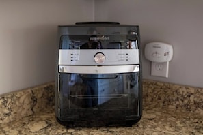 A kitchen with a built-in air fryer, a power outlet, and a granite countertop.