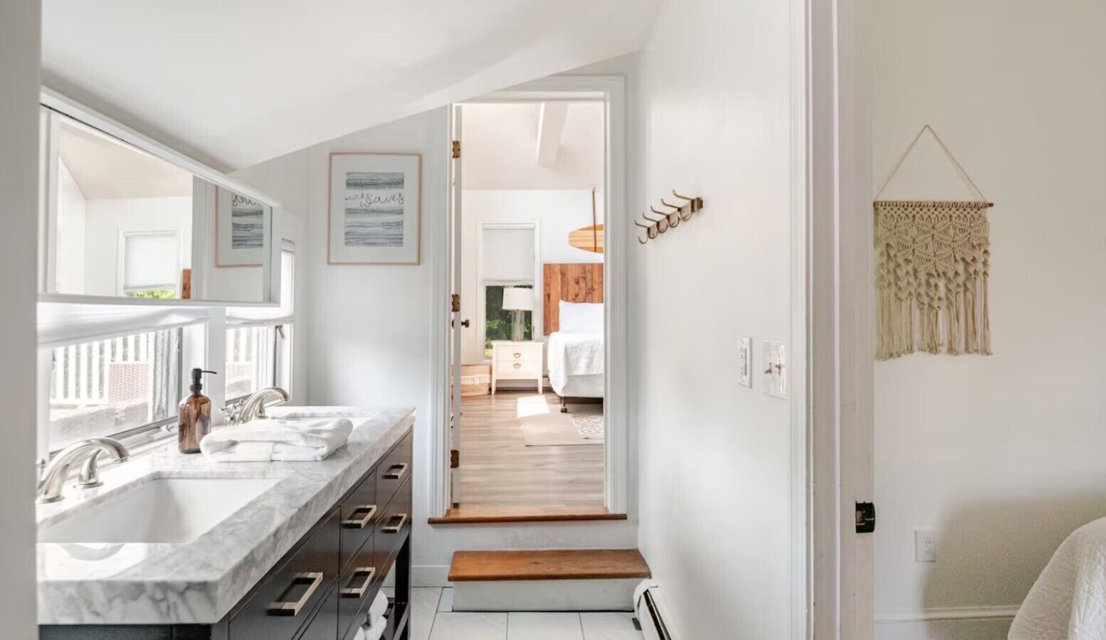 A modern bathroom with dual sinks, a large mirror, and a wooden bench.