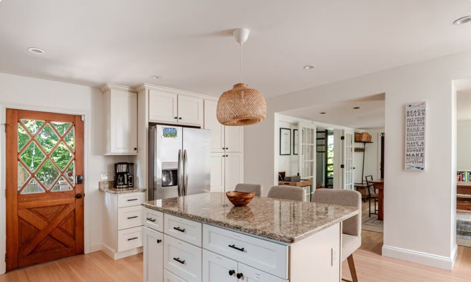 Una cocina moderna con armarios blancos, una isla central y una lámpara colgante.