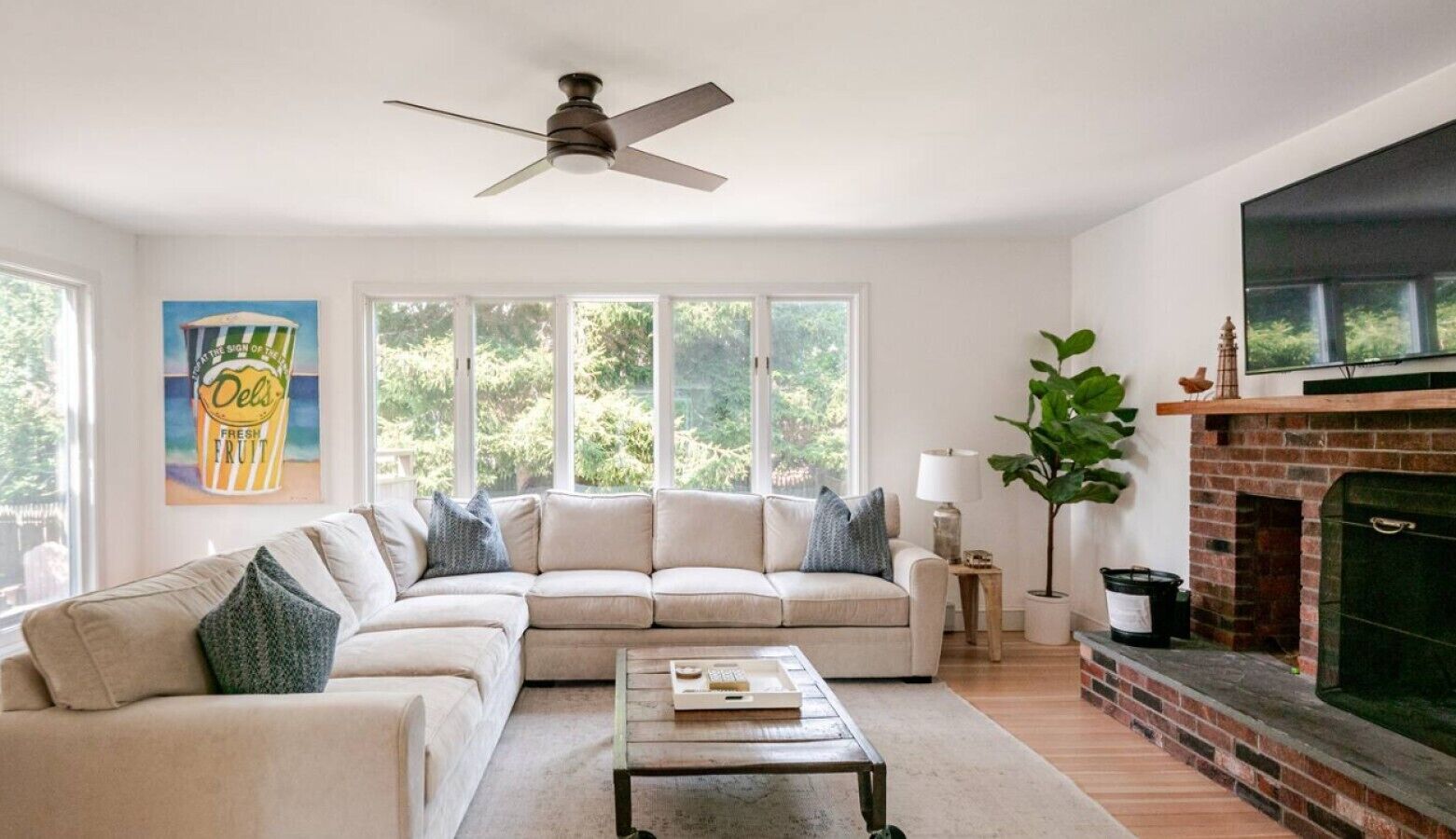A living room with a sectional sofa, a fireplace, and a large window.