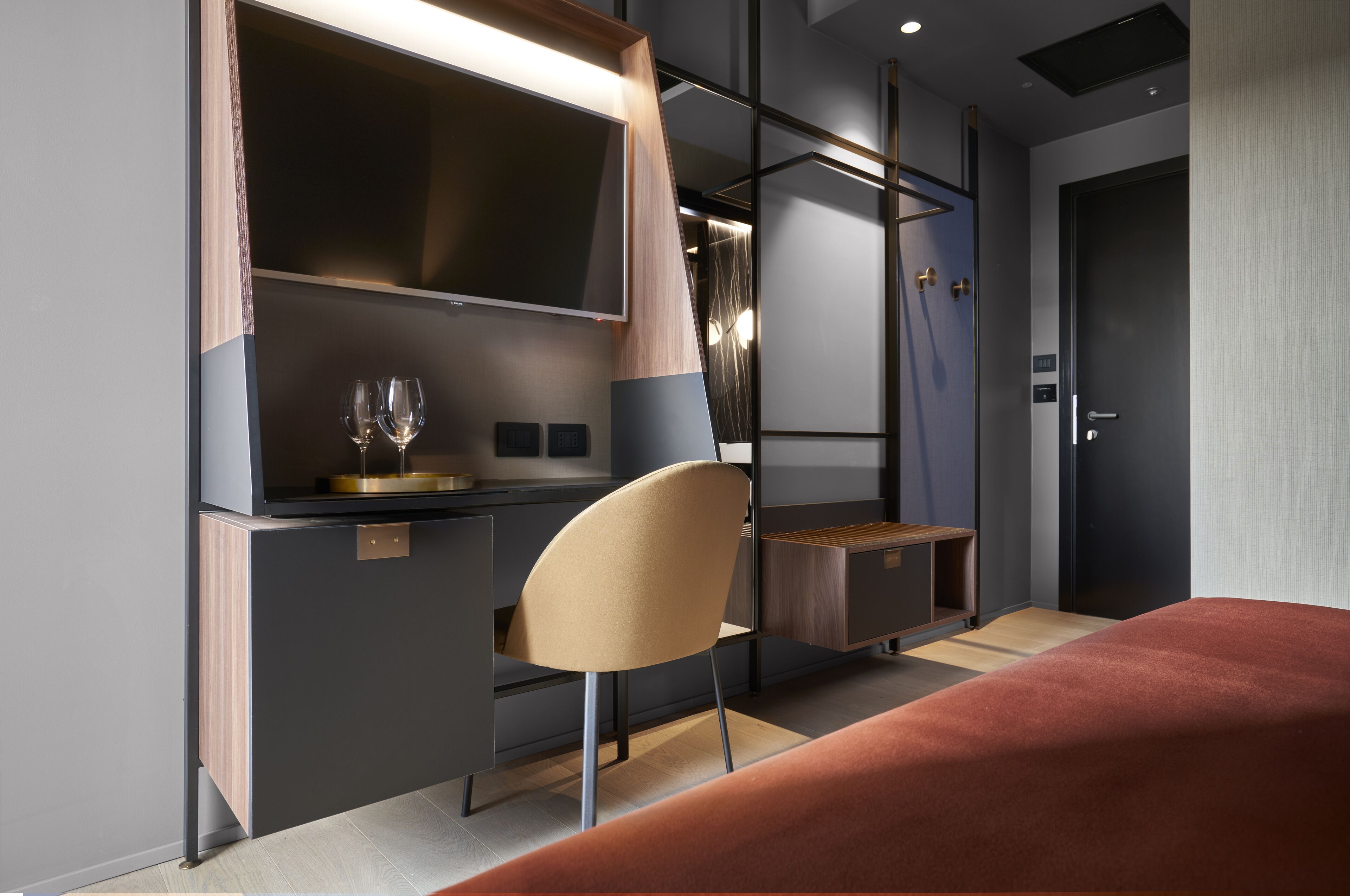 Una habitación de hotel moderna con cama, escritorio con silla, televisión y minibar.