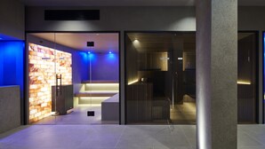 Un vestíbulo moderno con un panel de vidrio, un mostrador de recepción y una escalera que sube a un nivel superior.