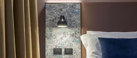 Una habitación de hotel con una cama, una mesita de noche con lámpara y una obra de arte colgada en la pared.