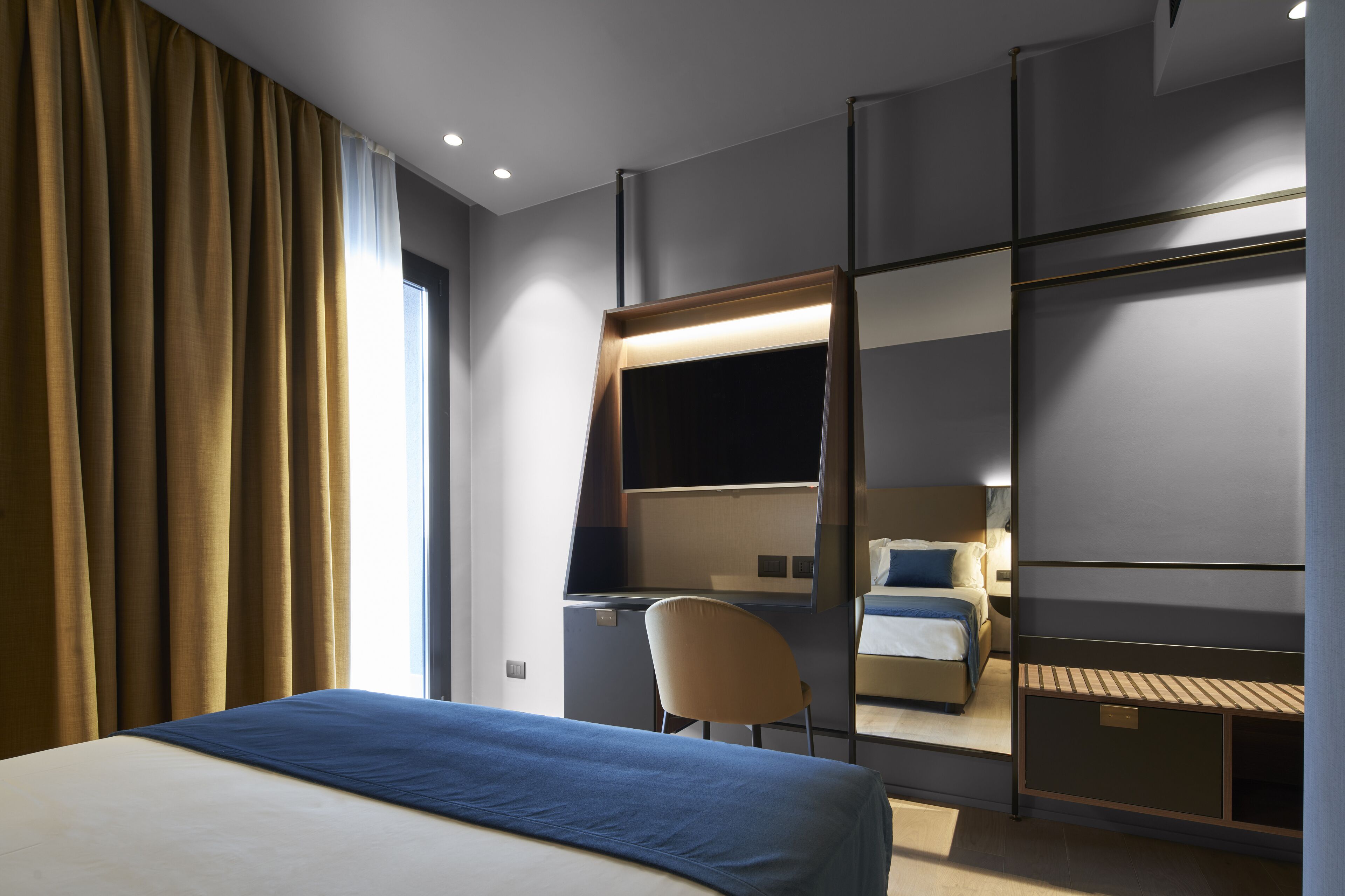 A modern hotel room with a large bed, a desk, and a chair.