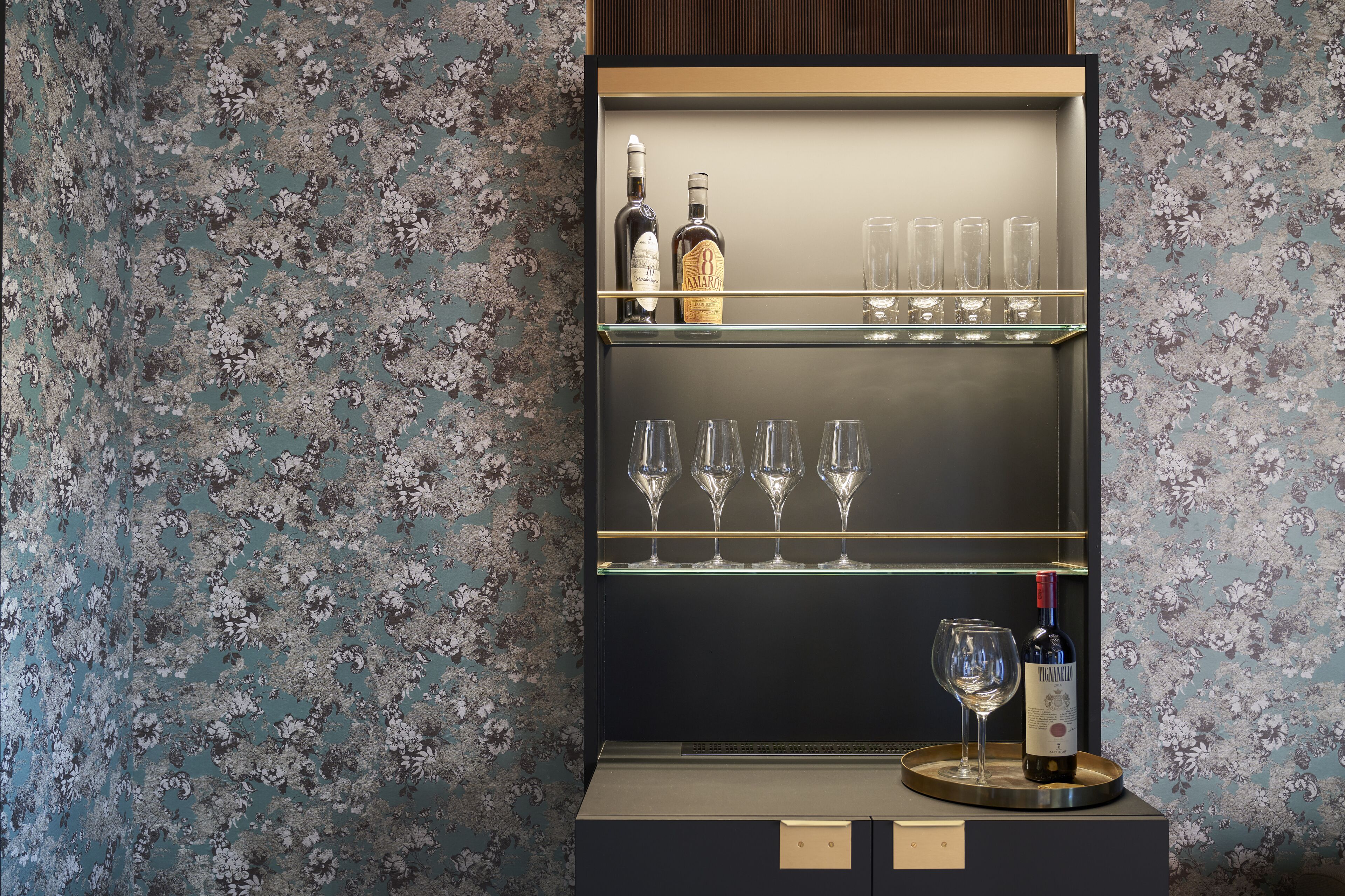 A bar area with two shelves, each holding bottles and glasses.