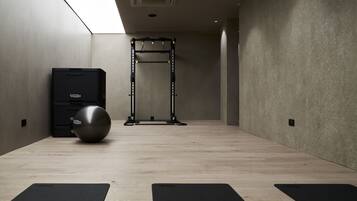Ein Fitnessstudio mit einer Klimmzugstange, einem Ergometer und einer Yogamatte.