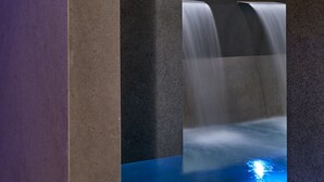 Un baño moderno con piso de azulejos azules, un lavamanos empotrado y una zona de ducha con mampara de vidrio.