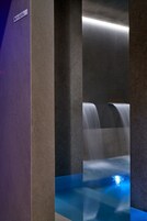 Un baño moderno con piso de azulejos azules, un lavamanos empotrado y una zona de ducha con mampara de vidrio.